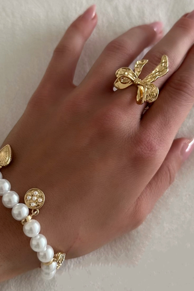 Guldfärgad ring med hamrad rosett